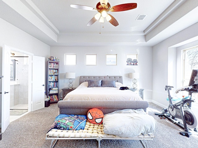 bedroom featuring ceiling fan, multiple windows, connected bathroom, and a raised ceiling