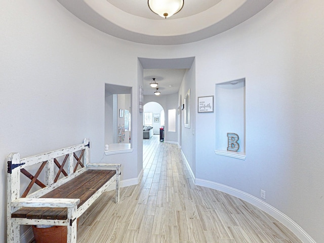 hall with a high ceiling and light wood-type flooring