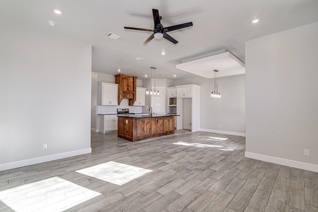 kitchen featuring ceiling fan, a center island, white cabinets, and hanging light fixtures