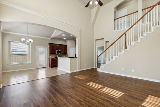 unfurnished living room with ceiling fan with notable chandelier, hardwood / wood-style flooring, and ornamental molding