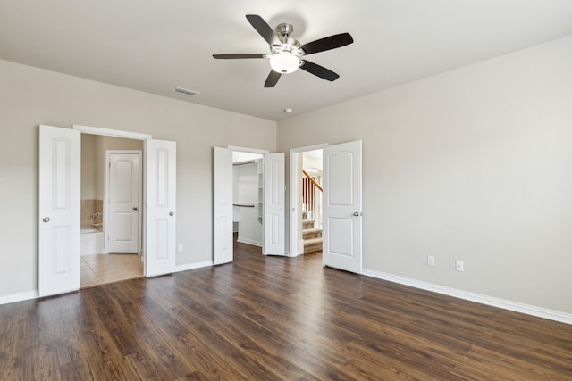 unfurnished bedroom featuring a walk in closet, ensuite bath, ceiling fan, dark hardwood / wood-style floors, and a closet