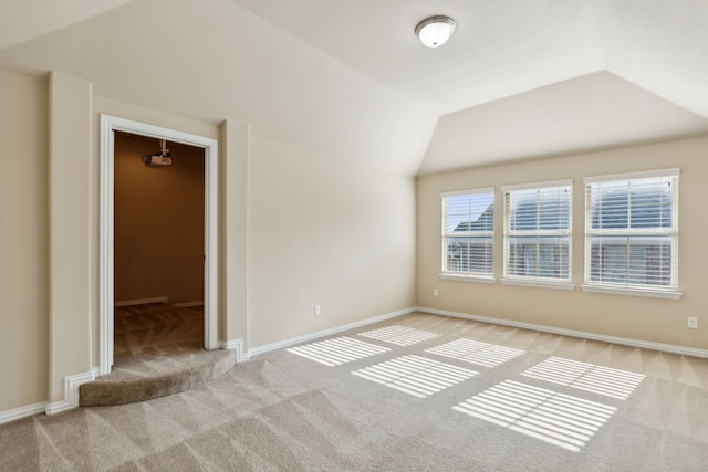 carpeted spare room featuring vaulted ceiling