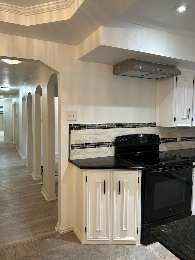 kitchen featuring white cabinetry, tasteful backsplash, black / electric stove, dark stone countertops, and crown molding