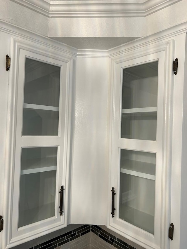 interior details with white cabinetry and ornamental molding