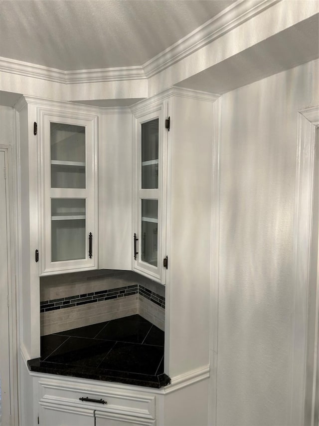 kitchen with white cabinetry, decorative backsplash, and ornamental molding