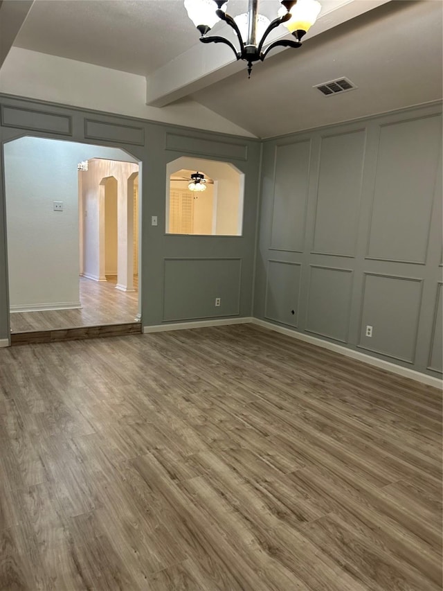 unfurnished room featuring beam ceiling, wood-type flooring, and ceiling fan with notable chandelier