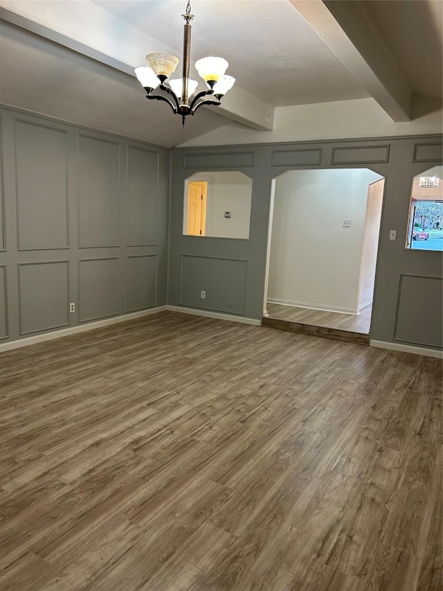 unfurnished dining area with beam ceiling, wood-type flooring, and a chandelier