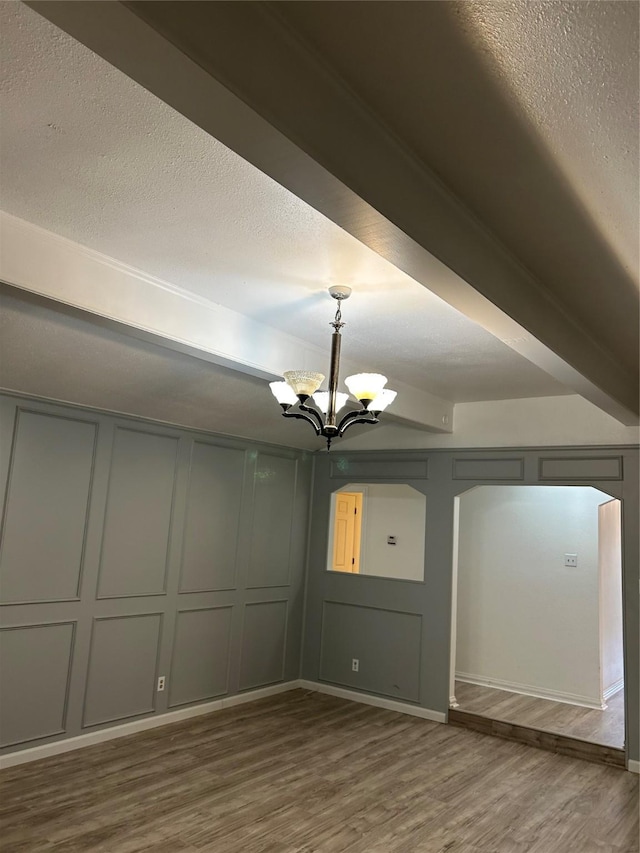 spare room featuring wood-type flooring, a textured ceiling, and an inviting chandelier