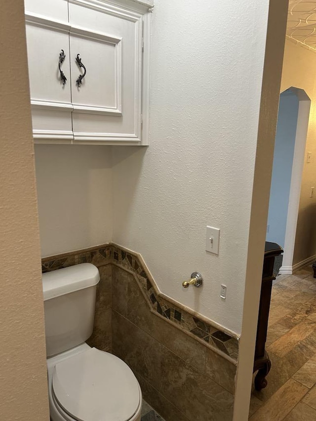 bathroom with toilet and tile walls