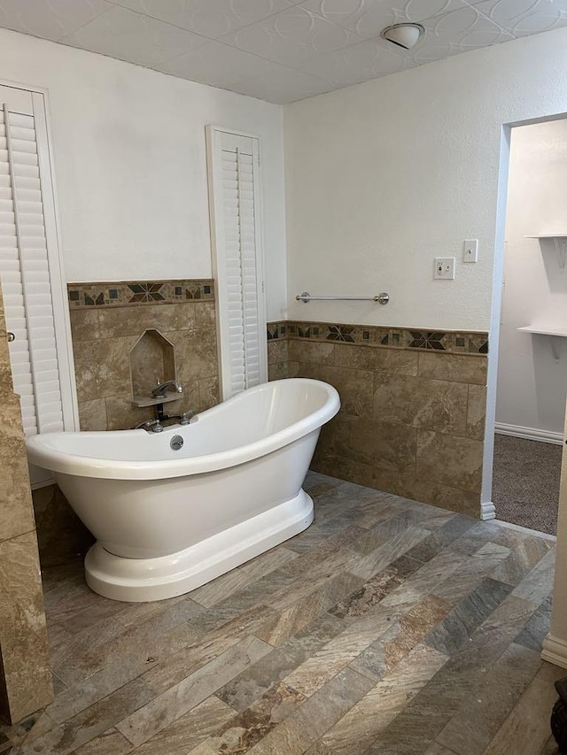 bathroom with a tub to relax in and tile walls