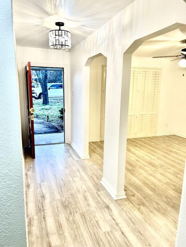 foyer featuring ceiling fan with notable chandelier and light hardwood / wood-style flooring