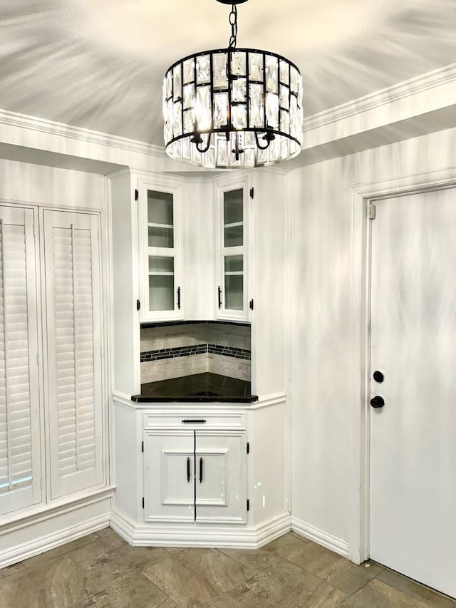 kitchen featuring pendant lighting, an inviting chandelier, crown molding, tasteful backsplash, and white cabinetry