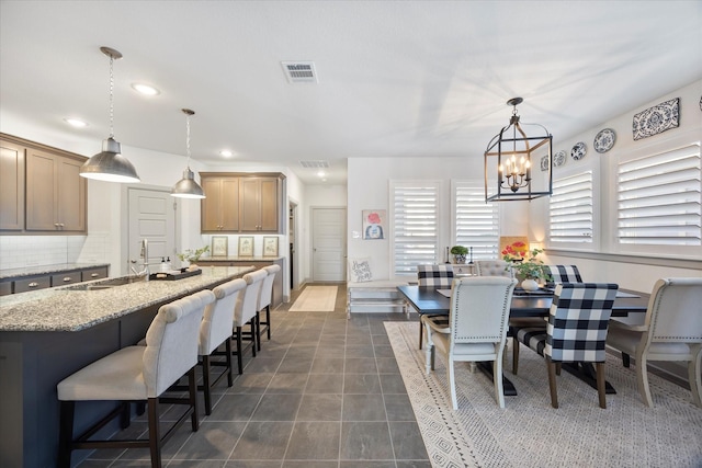 dining area featuring dark tile patterned flooring, a notable chandelier, and sink