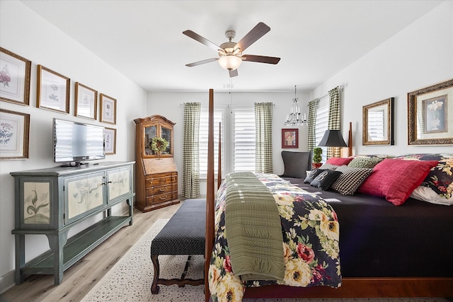 bedroom with ceiling fan with notable chandelier and light hardwood / wood-style flooring