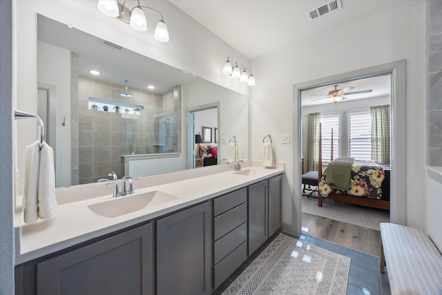 bathroom with ceiling fan, wood-type flooring, tiled shower, and vanity