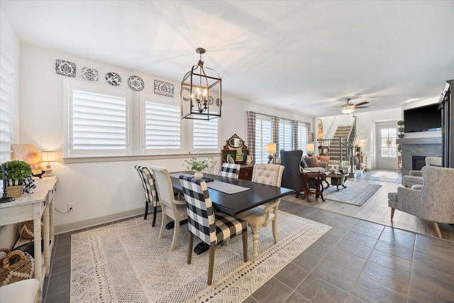 dining room with ceiling fan with notable chandelier and dark tile patterned flooring