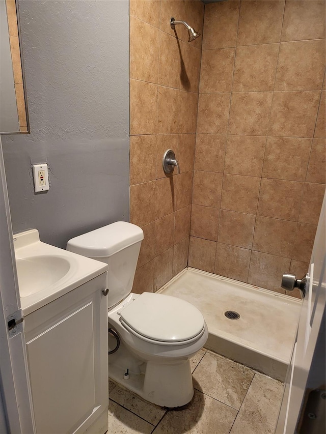 bathroom with toilet, vanity, and tiled shower