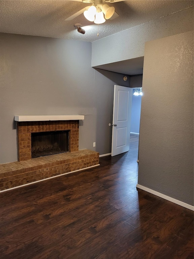 unfurnished living room with ceiling fan, a fireplace, dark hardwood / wood-style flooring, and a textured ceiling