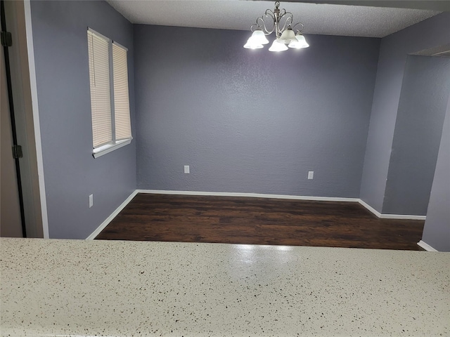 empty room with a chandelier and a textured ceiling