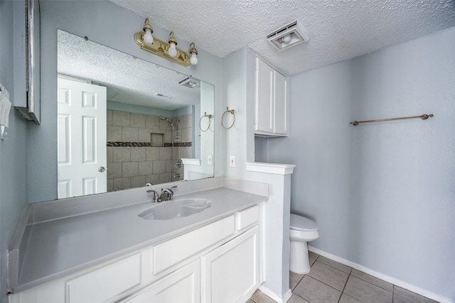 bathroom with vanity, tile patterned floors, toilet, a textured ceiling, and a tile shower