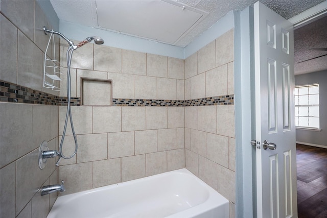 bathroom with a textured ceiling and tiled shower / bath combo