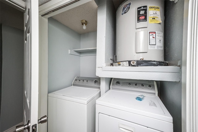 washroom featuring washing machine and clothes dryer, electric water heater, and a textured ceiling