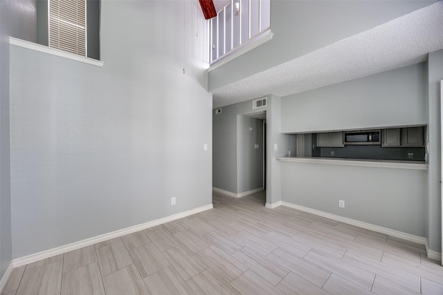 unfurnished living room featuring a towering ceiling