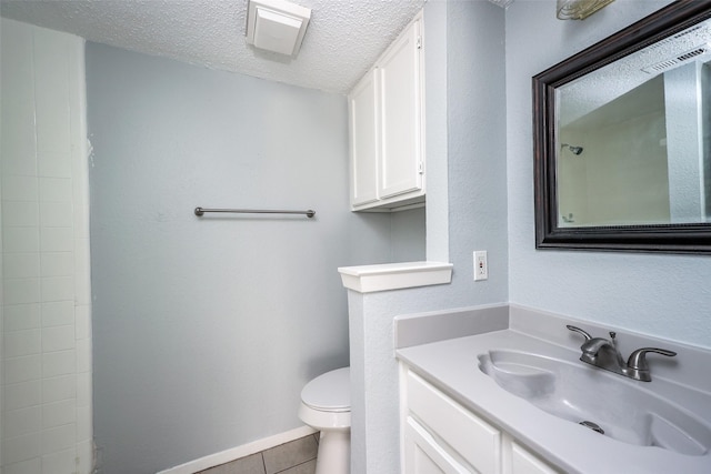 bathroom with tile patterned floors, vanity, a textured ceiling, and toilet