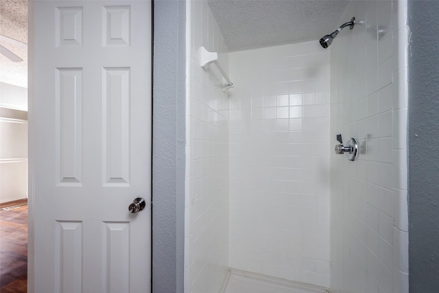 bathroom with a tile shower and a textured ceiling