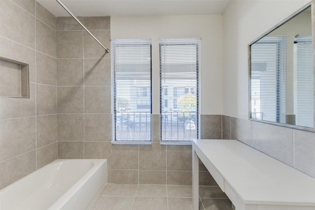 bathroom with tile patterned flooring, tiled shower / bath combo, and tile walls