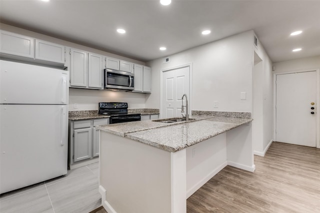 kitchen featuring kitchen peninsula, light stone countertops, sink, white refrigerator, and black / electric stove