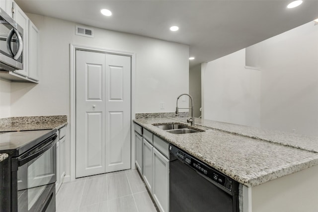 kitchen with black appliances, light stone counters, white cabinets, and sink