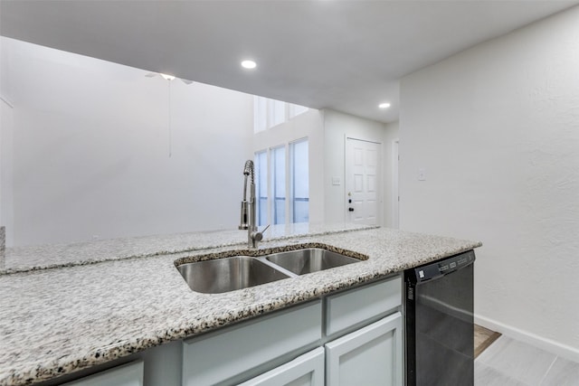 kitchen featuring light stone countertops, dishwasher, and sink