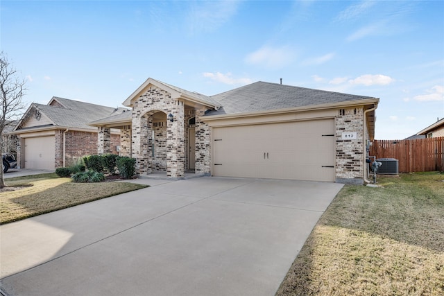 ranch-style home featuring a garage, a front lawn, and central air condition unit