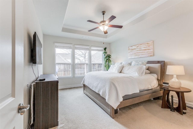 carpeted bedroom featuring a raised ceiling and ceiling fan