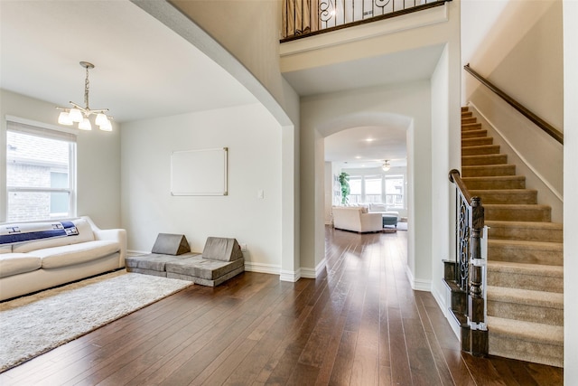 living room with ceiling fan with notable chandelier, dark hardwood / wood-style floors, and a wealth of natural light