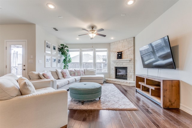 living room featuring a stone fireplace, ceiling fan, and dark hardwood / wood-style floors