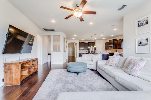 living room featuring ceiling fan and dark wood-type flooring