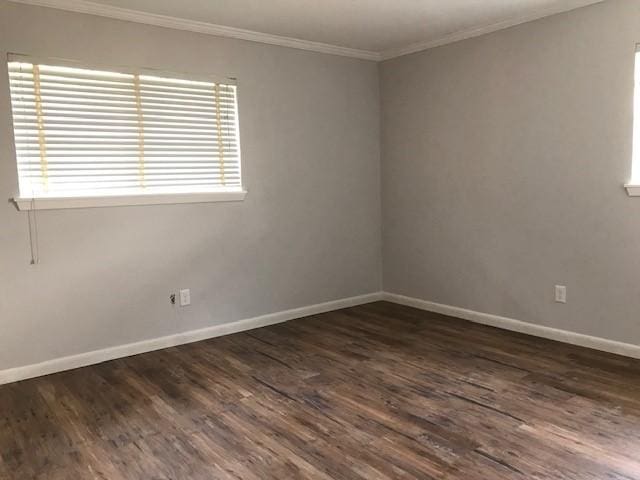 spare room with ornamental molding, dark wood-style flooring, and baseboards