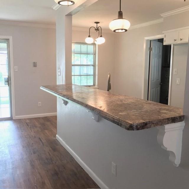 kitchen with a wealth of natural light, white cabinetry, and crown molding