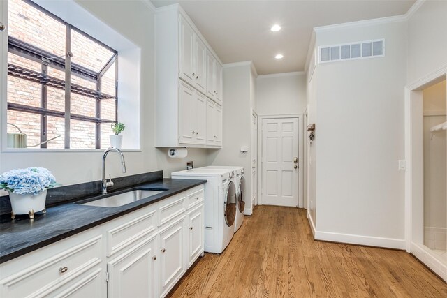 laundry room with crown molding, sink, light hardwood / wood-style flooring, washing machine and dryer, and cabinets