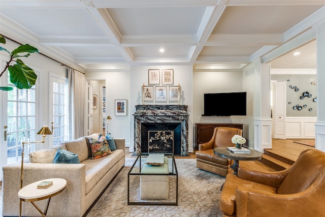 living room with beam ceiling, a fireplace, ornamental molding, coffered ceiling, and light hardwood / wood-style floors