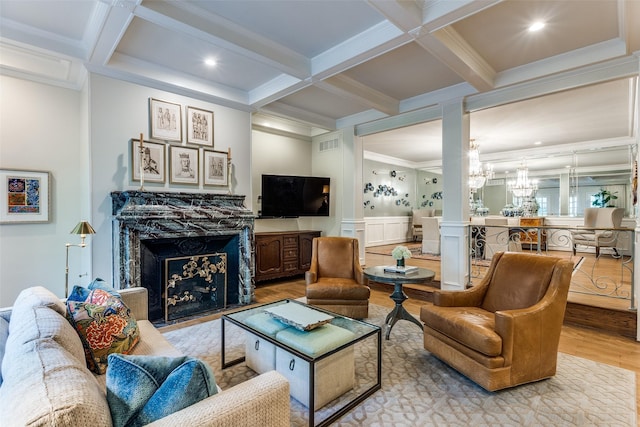 living room featuring a notable chandelier, beamed ceiling, coffered ceiling, light hardwood / wood-style flooring, and ornamental molding