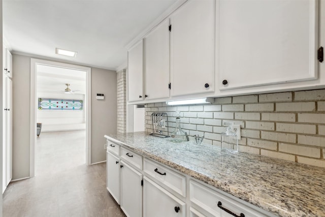 kitchen with decorative backsplash, light stone countertops, white cabinets, and ceiling fan