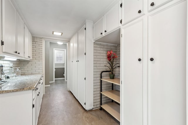 kitchen with light stone countertops and white cabinetry