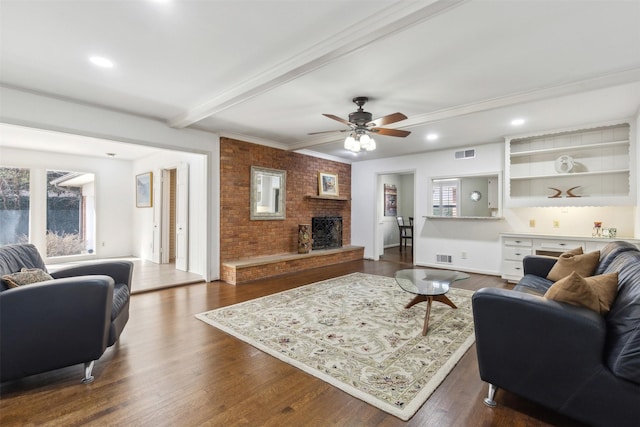 living room featuring ceiling fan, dark hardwood / wood-style floors, a fireplace, crown molding, and beam ceiling