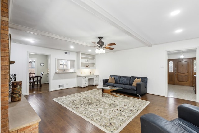 living room featuring ceiling fan, dark hardwood / wood-style flooring, beamed ceiling, and built in desk