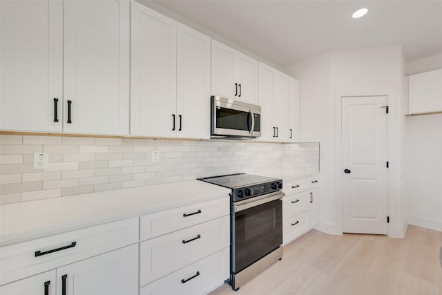 kitchen featuring backsplash, white cabinetry, light hardwood / wood-style floors, and appliances with stainless steel finishes