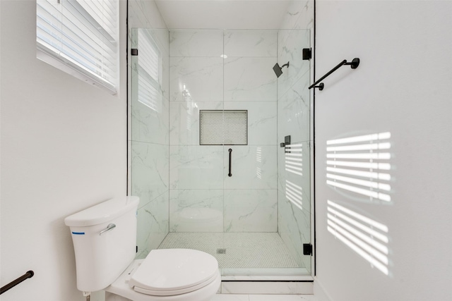 bathroom featuring toilet and a shower with shower door