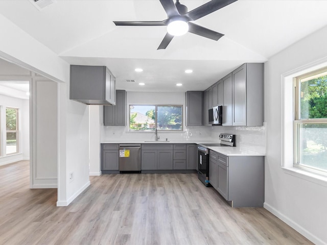 kitchen with gray cabinetry, stainless steel appliances, and vaulted ceiling